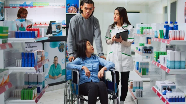 Pharmacy Employee Giving Pills Box Woman Wheelchair Male Caretaker Helping — Stock Photo, Image