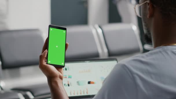 施設内待機中にスマートフォンのグリーンスクリーンテンプレートを使用している男性患者 若いです男を見て隔離されたモックアップディスプレイとクロマキー 携帯電話の画面上の空白のコピースペース — ストック動画