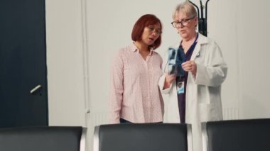 Kıdemli hekim ve hasta, röntgen taramasında kemik analizi yapıyor, check-up randevusunda ortopedik tanı hakkında konuşuyor. Lobide radyografi sınavı sonuçlarına bakıyorum. El kamerasıyla..