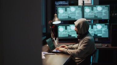 Programlama hırsızı siber güvenlik sunucusunu kırıyor ve birden fazla monitörden büyük veriler çalıyor. Kapüşonlu bilgisayar korsanı kulaklık kullanıyor ve virüs ile bilgisayar ve sistem kötü amaçlı yazılıma neden oluyor. El kamerasıyla..