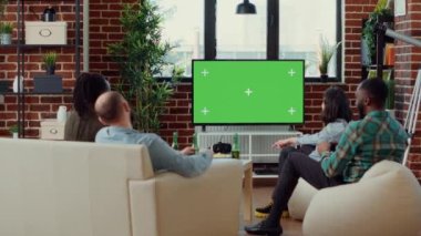 Bir grup insan TV 'de video oyunları oynamak için yeşil ekran kullanıyor, boş model şablonuna bakıyor. İzole edilmiş krom anahtar arkaplan üzerinde online oyun mücadelesi, televizyonda telif alanı.
