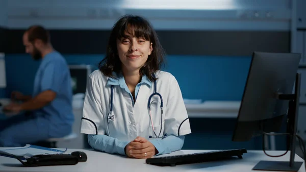 Uśmiechnięty Lekarz Stojący Przy Biurku Gabinecie Szpitalnym Pracujący Godzinach Służbie — Zdjęcie stockowe