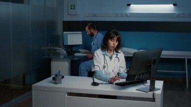 Hastane ofisinde gece geç saatlere kadar tedavi görürken hasta raporlarını kontrol ettikten sonra panoya tıbbi uzmanlık yazısı yazan pratisyen hekim. Sağlık hizmeti ve konsept