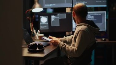 Erkek bilişim mühendisi, dosya ve ekranlardaki web verilerini analiz ediyor, dosyalardaki bilgileri karşılaştırıyor. Genç adam programlama dili kullanıyor ve geceleri yeni kullanıcı arayüzü kodluyor.