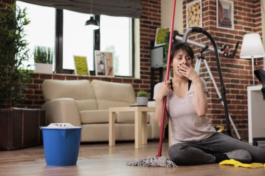 Bitkin düşmüş ev hanımı oturma odasında paspas ile mutsuz bir şekilde oturuyor, ev işi yapıyor, hayal kırıklığına uğramış hissediyor. Kadın bütün gününü temizlik yaparak geçiriyor, ev işlerini yardım almadan yapıyor..