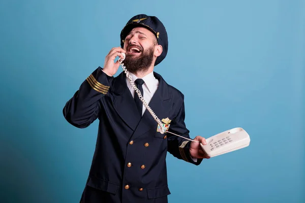 中年の航空会社の船長は 固定電話で話をし 電話を持ち 会話をしている プロの飛行制服を着た笑顔のパイロット空港での応答コール スタジオメディアショット — ストック写真
