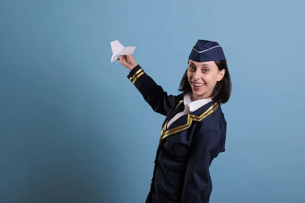 Flugbegleiterin Hält Papierflieger Der Hand Während Sie Die Kamera Schaut — Stockfoto