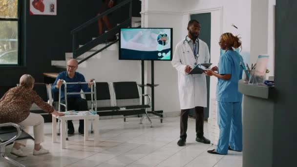 非裔美国人专家小组在医院接待处大堂谈论预约和疾病治疗 在医疗中心工作并讨论医学的护士和医生 — 图库视频影像