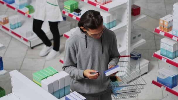 Νεαρός Κοιτάζει Κουτιά Φάρμακα Στο Φαρμακείο Διαβάζοντας Πακέτο Για Αγοράσει — Αρχείο Βίντεο