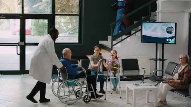 Starszy Mężczyzna Wózku Inwalidzkim Próbuje Chodzić Ramą Poczekalni Rozmawiając Kobietą — Wideo stockowe