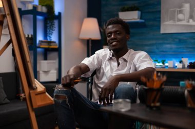Sanat stüdyosunda kronik dejeneratif hastalığı olan gülümseyen bir sanatçı. Sanatsal becerileri olan Afrikalı bir Amerikalı motor nöron sağlık durumuyla yaşıyor elinde renkli kalemler, atölyede resim çiziyor..