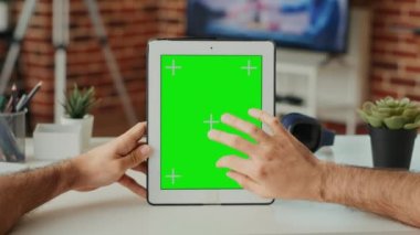 Ofis çalışanı yeşil ekran şablonlu dijital cihaz kullanıyor. Dikey olarak taşınabilir tablet ve izole ekran kullanıyor. Boş krom anahtar arkaplanıyla çalışmak ve ekranı taklit etmek. Kapat..