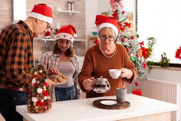 一家人在圣诞装饰的厨房里一起庆祝圣诞节 吃着烘焙的饼干 喝咖啡 在寒假期间享受圣诞节快乐的孙子孙女 — 图库照片