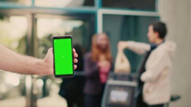 Dışarıdaki akıllı telefondan yeşil ekran görüntüsünü gösteren kişi. Müşteri kapısında yemek siparişi veren kurye. Kopyalama alanı ile izole edilmiş model şablonu kullanılarak, krom anahtarlı cep telefonu tutuluyor.