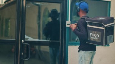 Afro-Amerikan uçak gemisi hazır yemek siparişi vermek için kapı zilini çalıyor. Paket paket taşıyordu. Restoran kuryesi ofis binasındaki müşterilere yemek servisi yapıyor. El kamerasıyla..