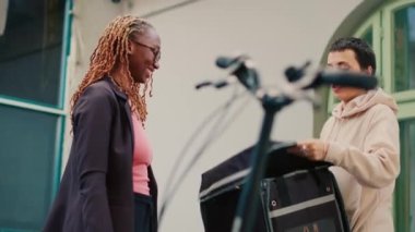 Kadın müşteri yemek siparişi ve fast food dağıtım hizmetleri için kredi kartı kullanıyor. Kurye postane terminalini tutuyor ve müşteri restoran paketini almak için bağlantısız kart kullanıyor. El kamerasıyla..