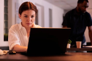 Çalışan bir şirket çalışanı, laptop tarayıcısında web sitesi kullanıyor, proje yöneticisi bilgisayarda yazıyor. Çalışma alanındaki pazarlama raporunu analiz eden işçi, çalışma masasındaki kadın