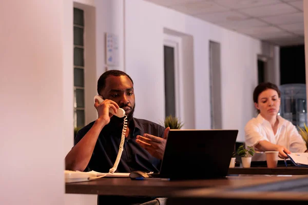 办公室经理通过固定电话与客户讨论项目计划 非洲裔美国秘书接听电话 与同事交谈 在同事间进行电话交谈的人 — 图库照片
