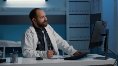 Doktor, video görüşme konferansı sırasında ekiple tıbbi uzmanlığı tartışıyor. Doktor gece geç saatlere kadar Hopsital Ofis 'te çalışıyor. Sağlık tedavisi planlıyorlar.