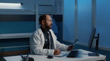 Kafkasyalı pratisyen doktor hasta ciğerlerini analiz ediyor. Radyografi, bilgisayardaki tıbbi uzmanlığı kontrol ediyor. Sağlık görevlisi muayene sırasında saatlerce hastane ofisinde çalışıyor.