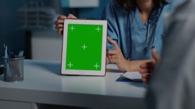 Muayene sırasında hastanın tıbbi uzmanlığını tartışırken, doktorlara yeşil ekran şablonlu tablet bilgisayarı gösteren asistan. Klinik personeli gece geç saatlere kadar hastane ofisinde çalışıyor.