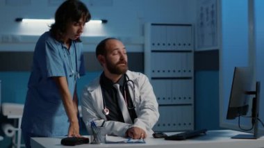 Uzman ve hemşire hasta raporlarına bakıyor. Hastalık belirtilerini tartışıyorlar. İlaç tedavisi planlıyorlar. Klinik personeli mesai saatleri dışında hastane ofisinde çalışıyor. Tıp konsepti