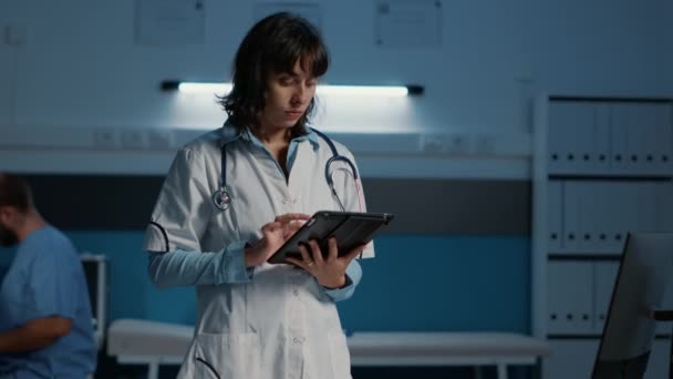 Pratisyen Doktor Elinde Tablet Tutarken Hasta Raporlarını Kontrol Ederken Hastane — Stok video
