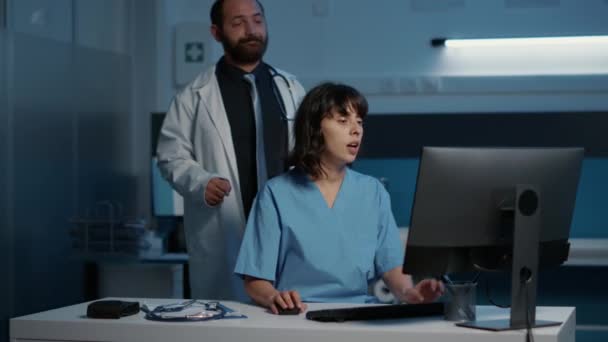 Pielęgniarka Stojąca Przy Biurku Pisząca Ekspertyzę Medyczną Komputerze Podczas Gdy — Wideo stockowe