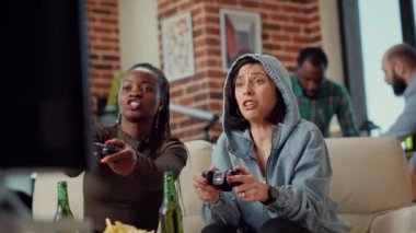 Heyecanlı bir grup arkadaş video oyunlarının kazanmasını kutluyor, TV oyun konsolu ile çevrimiçi yarışmayı kazandıkları için mutlu hissediyorlar. Televizyonda meydan okuyan neşeli kadınlar. El kamerasıyla..