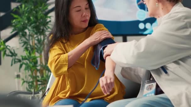 待機室でアジアの老婦人に対する高血圧や脈圧を測定する高齢の医療 低血圧や心臓検査を確認するために心臓機器を使用してください 手持ち撮影 — ストック動画