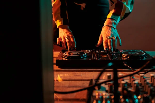 Female musician using mixing turntables to play music at party, having fun with audio dj equipment for techno performance. Playing stereo sounds with electronics, microphone and headphones.