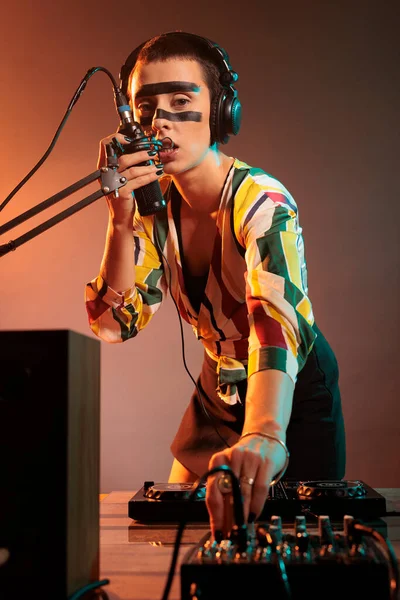 Musician girl using mixer turntables for musical performance, mixing techno music as dj performer. Cool artist adjusting volume and bass key on electronics stereo equipment, audio insturment.