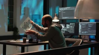 Veritabanı geliştiricisi masadaki bir şeyi arıyor, html betiği ile uygulama programlama üzerinde çalışıyor. Dosya arayan genç adam, yapay zeka bulut hesaplama arayüzü.