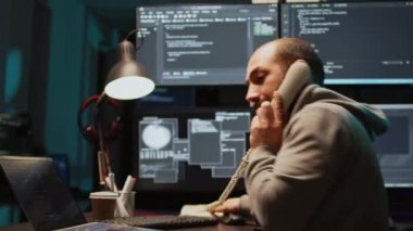 Veritabanı yöneticisi gece geç saatlerde ev telefonuna cevap veriyor, telefon kablosuyla konuşuyor ve kaynak kodunu daktilo ediyor. Şirket ajansı için algoritma oluşturuluyor, Html senaryo yazılıyor. El kamerasıyla..