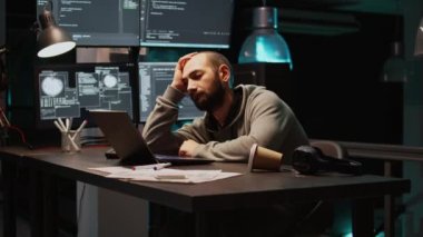 Uyuyan bilişim mühendisi yorgun ve programlama üzerinde çalışıyor, uygulama geliştirme işinde uyuyakalıyor. Veritabanı sunucu sistemi oluşturmak için yeni arayüzle çalışan genç yetişkinler. El kamerasıyla..
