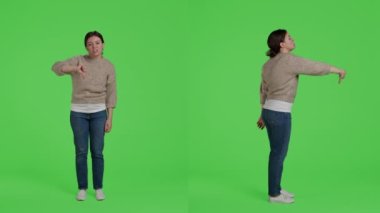 Kadın model kamerada olumsuz işaretler gösteriyor. Onaylamıyor ve kötü bir sembol çiziyor. Kendine güveni tam bir kadın tüm yeşil ekran üzerinde hoşnutsuzluk jesti ile anlaşmazlık ifade.
