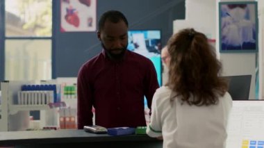Afro-amerikan müşteri NFC cep telefonu ödemesini eczaneden takviye ve uyuşturucu almak için kullanıyor, kasada ödeme yapıyor. Bağlantı kurulamayan terminal ve sağlık hizmetlerinden ilaç satın almak.