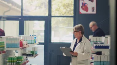 Reçeteli kağıtları olan bir erkek hasta, tedavi hakkında uzmanlara soru soruyor, eczane raflarından ilaç ve vitamin satın almak istiyor. Eczanedeki malzeme kutularını işaretliyorum..