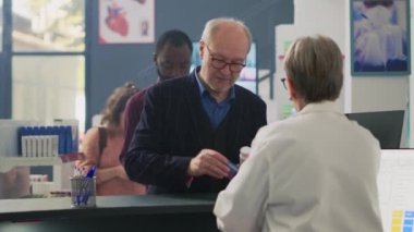 Eczane tezgahından ilaç almak isteyen müşteriler, Ukala, kredi kartı ve cep telefonu kullanarak pos terminalinde ödeme yapmak istiyorlar. İlaç ürünleri satın almak. Üçayak atışı.