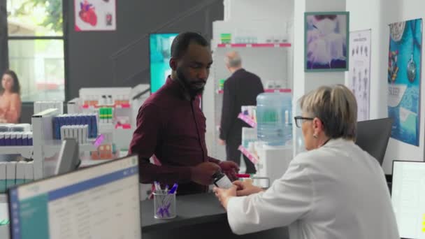 Африканский Американец Спрашивает Фармацевта Бутылке Таблеток Рассматривает Лекарства Витамины Купить — стоковое видео