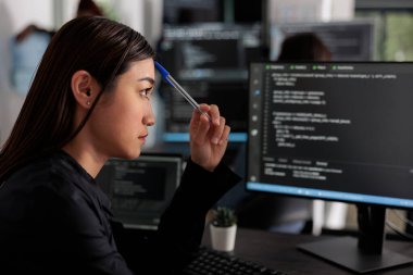 Düşünceli Asyalı programcı Html senaryo geliştirmede düşünüyor, Html kodu yaratmak için beyin fırtınası yapıyor. Yazılım bürosundaki veritabanı sunucusunda çalışan yazılım geliştiricisi