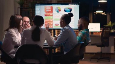 Çeşitli iş arkadaşları iş toplantısında beyin fırtınası yapıyor, analitik sunumu tartışıyorlar. Meslektaşlar arası iletişim, insanlar gece vakti ortak çalışma odasında konuşuyorlar.
