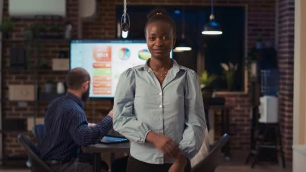 微笑着的非洲裔美国女商人穿过臂弯的肖像 前视镜中弹 公司员工站在合作空间的会议室门口 同事们做背景介绍 — 图库视频影像