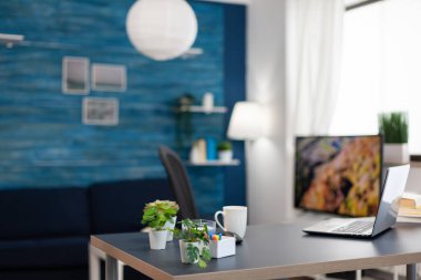 Boş dairedeki ofis masasında küçük çiçekler. Güzel iç tasarımı olan hiç kimsenin olmadığı rahat bir oturma odası..