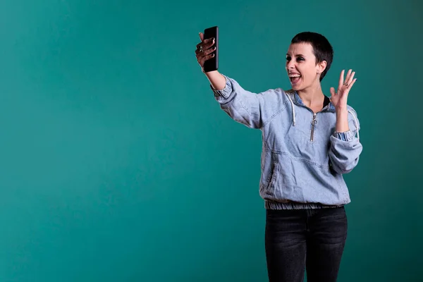 吸引自信的女人通过在线智能手机视频问候远方的朋友 同时站在独立的工作室背景上 打电话给快乐的女性在电话会议上挥手 — 图库照片