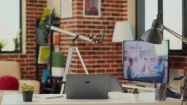 Uzaktan çalışmak için dizüstü bilgisayarı olan boş bir çalışma masası, yeni bir iş öğrenmek için dairede bilgisayar kullanan yaratıcı bir çalışan. Oturma odasındaki bilgisayar muhasebe ve pazarlama işine alışkındır..