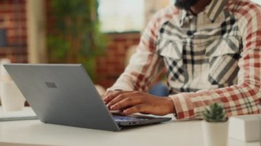 Genç adam şirket bilgisayarında online veri yazıyor, evde uzaktan kumanda yapıyor ve iş ağını kullanıyor. Finansal rapor üzerinde çalışıyorum pazarlamayı analiz ediyorum, internetten öğreniyorum. El kamerasıyla..