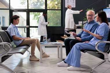 Hastane lobisindeki sağlık kontrolünde tıbbi belgeleri imzalamadan önce kıdemli hastaya ilaç tedavisini açıklayan uzman bir asistan. Sağlık hizmeti ve konsept