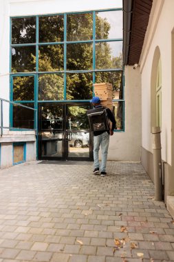 Teslimatçı, büyük pizza kutularını ofisin arka gözüne yığıyor, kurye dışarıda yemek siparişini tutuyor. Afro-Amerikan işçiler fast food dağıtımı yapıyor.