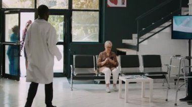 Yaşlı bir kadınla sağlık kontrolüne katılan erkek doktor, hastayı kabineye götürüp konsültasyona başlıyor. Genç adam klinikte hasta ile tıbbi muayenede..